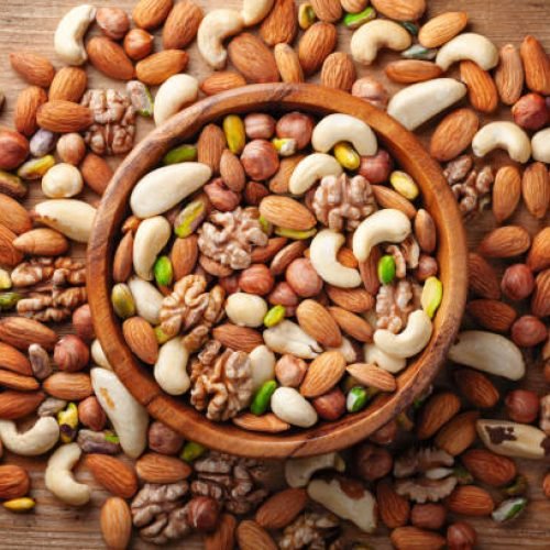 Wooden bowl with mixed nuts on rustic table top view. Healthy and nutrient food and snack.